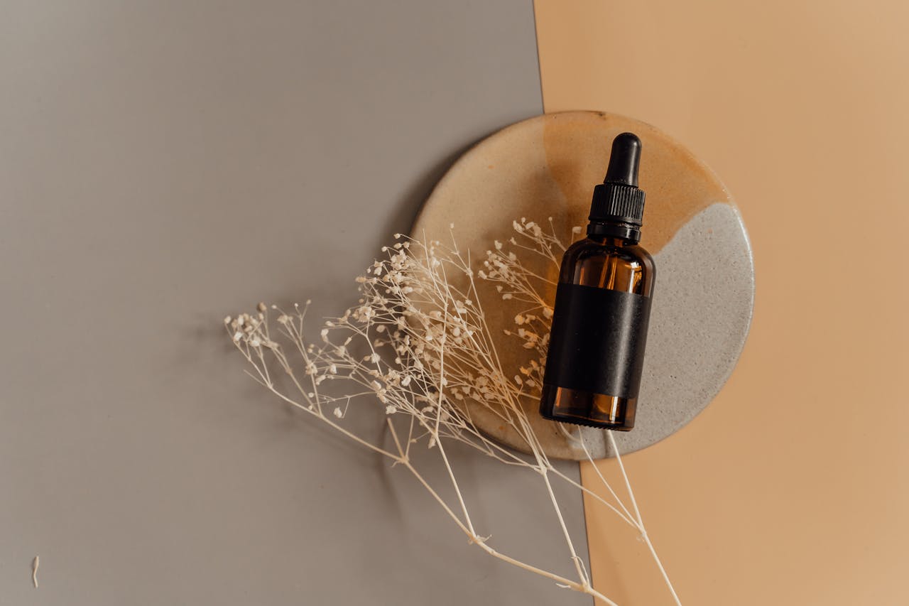 services-03 Aesthetic flatlay of a cosmetic dropper bottle on a minimalist background with dried flowers.